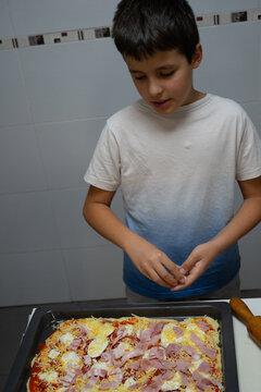 A child adding ingredients to a pizza