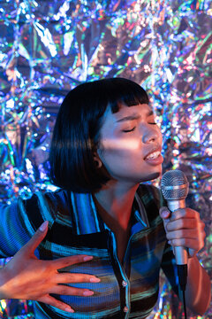 Young Latin woman singer performing with microphone on stage