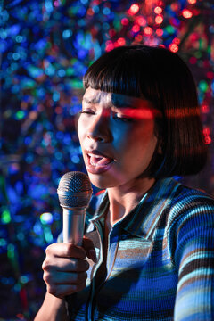 Young Latin woman singer performing with microphone on stage