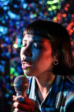 Young Latin woman singer performing with colorful bokeh