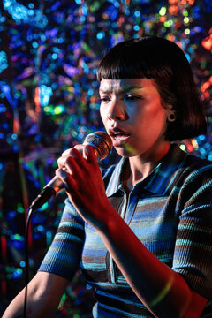 Young Latin woman singer performing with microphone on stage