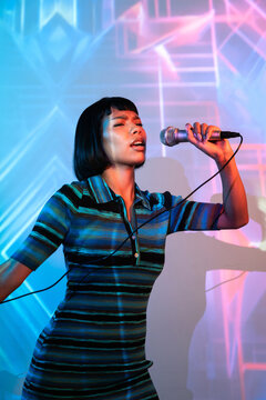 Young Latin woman singer performing with neon stage light