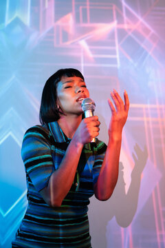 Young latin woman singer performing with microphone on stage