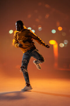 Black man urban dancer in hoodie jumping at night