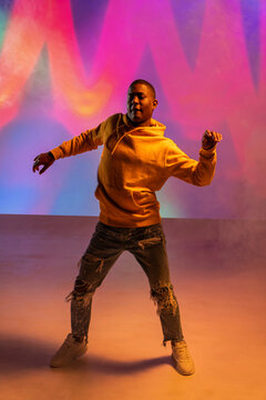 Urban dance move by black man in neon light studio set