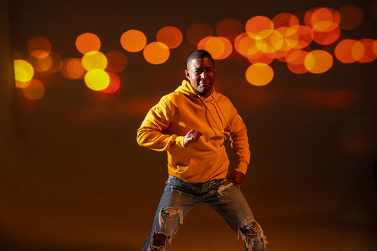 Urban dancer in yellow hoodie posing with bokeh lights