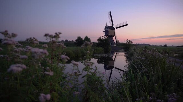 Broekmolen Windmill at Twilight in the Netherlands, Historic Dutch Polder Landscape with Vibrant Pastel Sunset Reflection in a Calm Canal.