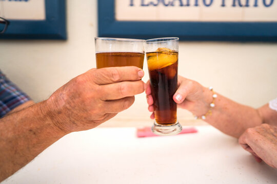 Two people toasting with drinks in casual setting