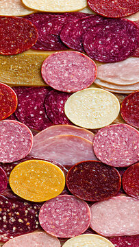 A colorful and appetizing close-up of various thinly sliced deli meats, including salamis and hams, meticulously arranged