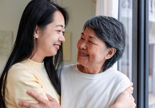 Loving embrace between mother and daughter by window