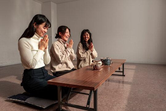 Japanese tea ritual with women kneeling and hands together