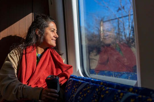 Woman enjoying quiet train ride with coffee by window