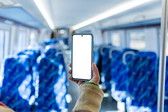 Hand holding smartphone with blank screen on train interior