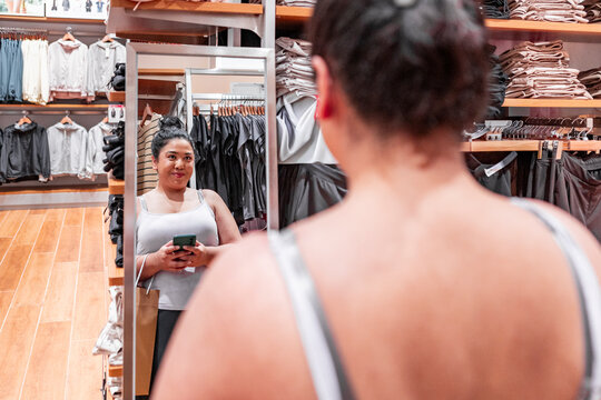 Woman checking outfit in store mirror while shopping alone