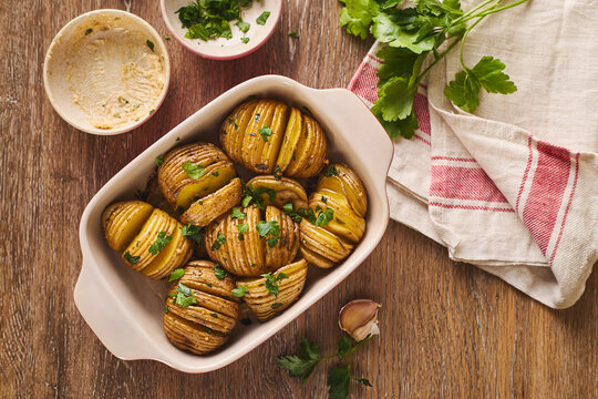 Hasselback roasted potato in baking dish on rustic table