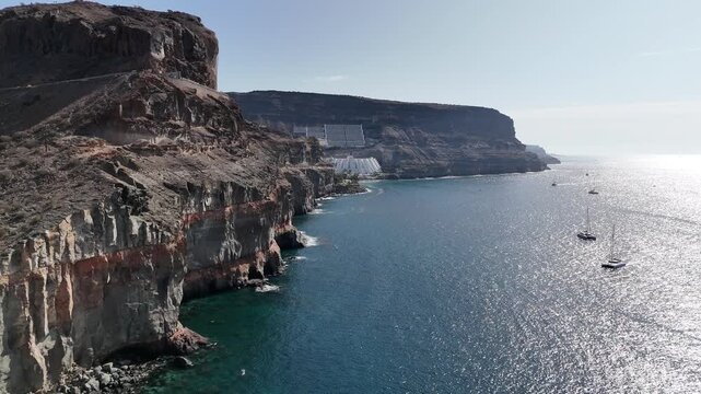 Aerial panorama flight along coastal cliff and Atlantic ocean towards hotel in Puerto de Mogan on Canary Island Gran Canaria