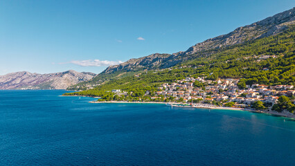 Obraz premium Aerial view of the coastal town of Brela on the Makarska Riviera in Croatia, featuring Mediterranean architecture, pine forests, and the Adriatic Sea