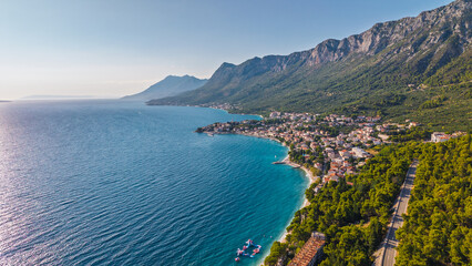 Obraz premium Aerial view of the Adriatic coastline in Croatia with turquoise sea, pine forests, and a coastal town nestled at the foot of the mountains