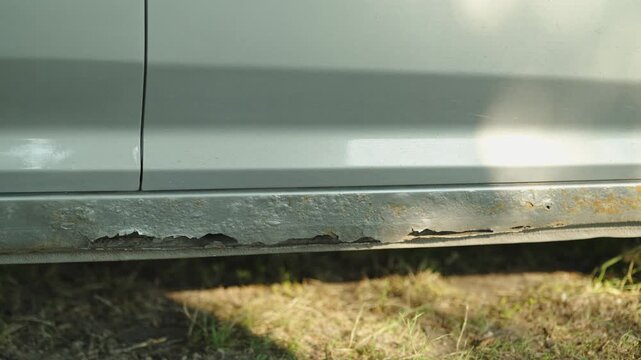  Severe rust and corrosion damage the rocker panel of silver car