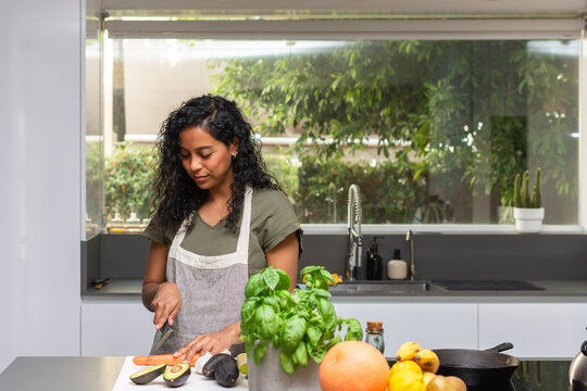 Hispanic woman preparing fresh vegetables in modern kitchen