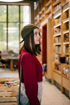 Young woman browsing bookshelves in a modern library interior