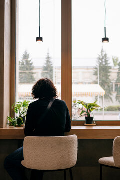 Solitary person sitting by cafe window with plants