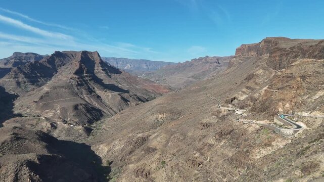 Aerial panorama flight with mountain, road and canyon Fataga ravine (barranco de Fataga) seen from viewpoint Mirador Degollada de las Yeguas on Canary Island Gran Canaria, Spain
