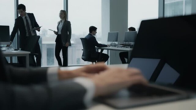Closeup of employees hands typing email reminders on a laptop main subject clear while background office activity softly fades.