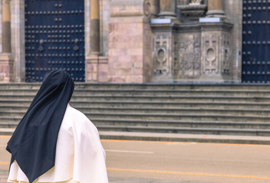 Catholic nun facing historic colonial cathedral entrance