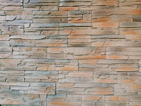 Premium commercial texture background of a modern decorative stone wall cladding with earthy tones. This high-resolution flat lay photography showcases structured faux slate or sandstone blocks featur