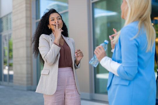 Businesswomen talking during a break enjoying vape in city