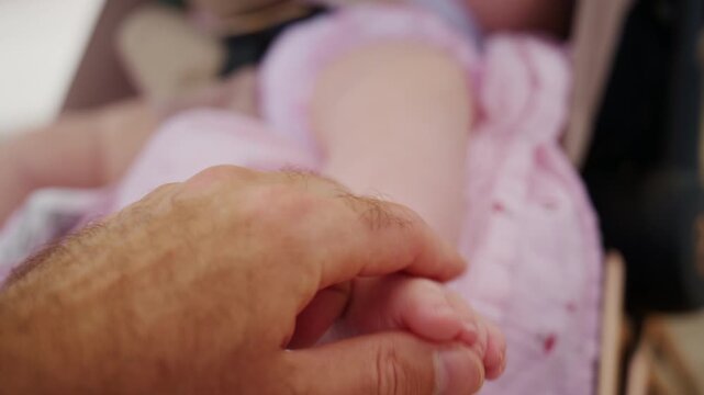 Parent hand gently holding small new born child foot. Concept of family, care, bond, tenderness, infancy and childhood