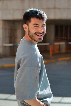 Smiling young man turning back in sunny urban street