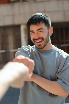 Smiling man reaching out for handshake outdoors in sunlight