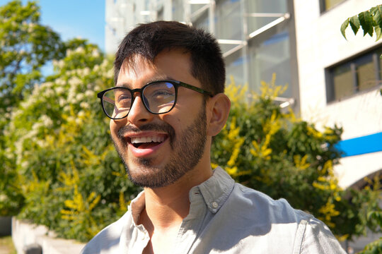 Smiling man with glasses outdoors in sunny urban setting