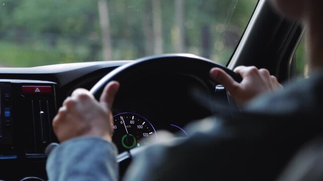 Woman driving a car through a scenic forest road. Driver holding steering wheel on trip. Automotive travel concept with nature background and dashboard view.