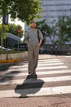 Young man crossing city street near office building
