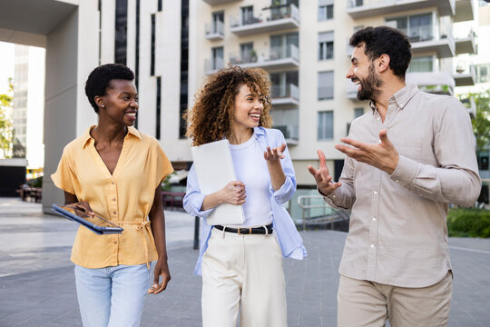 Colleagues chatting outside modern apartment complex