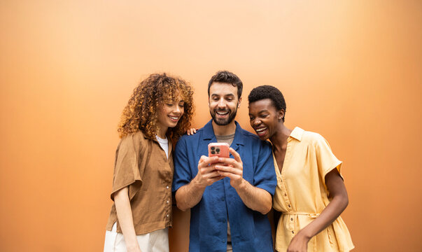 Friends laughing together while watching a smartphone screen