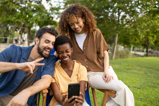 Friends taking selfie on smartphone in sunny park outdoors