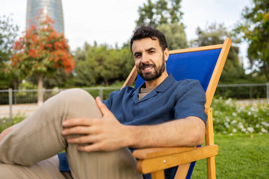 Relaxed man sitting in deck chair in city park outdoors