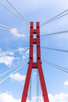 Red cable-stayed bridge pylon and steel cables in sky