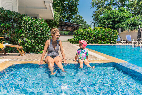 Grandmother and granddaughter relaxing by a sunny pool