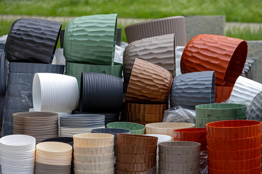 Decorative colourful plastic and ceramic flowerpots pile outside in garden