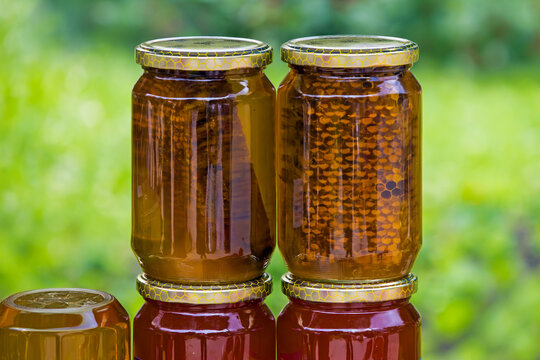 Homemade organic honey with honeycomb inside glass jars sold on local market