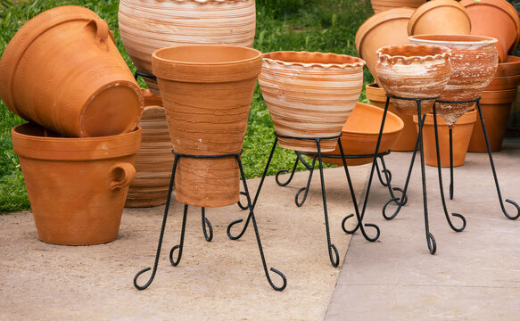 Terracotta planters on iron stands made from red clay and may feature decorative ribbing or textured finishes