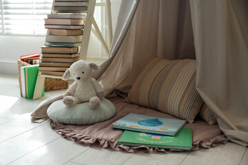 Beautiful wigwam, toy sheep and books in child's room. Interior design © New Africa