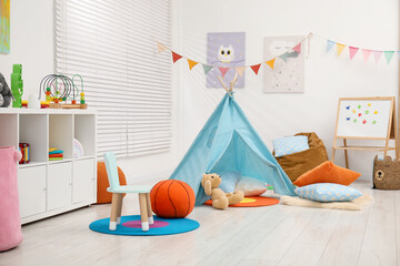 Beautiful wigwam with soft pillows, toys and magnetic board in child's room © New Africa