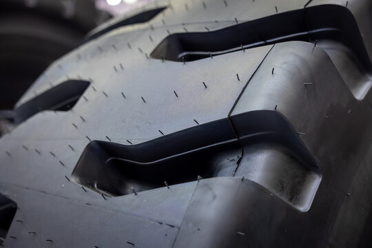 Macro shot of massive industrial tire tread pattern for heavy construction machinery. Professional rubber texture and technical detail of durable tractor wheel. Automotive engineering equipment