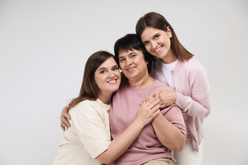 Fototapeta premium Happy family. Twin sisters and their mother on light background